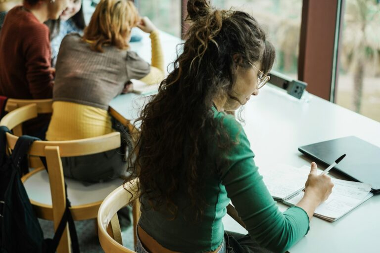 Young group of students studying inside university library - Focus on right girl hand